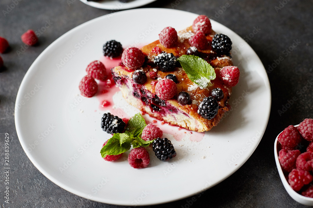 Piece of pie with blueberries, rasberry and mint for dessert on a white plate, napkin. Pieces of delicious homemade cake on a wooden boards background Piece of pie with blueberries, rasberry and mint for dessert on a white plate, napkin. Pieces of delicious homemade cake on a wooden boards background