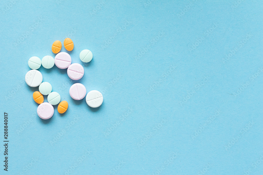 assorted medicine pills on light blue background.