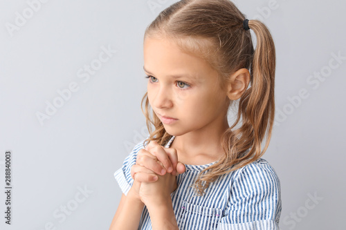 Praying little girl on ligh...