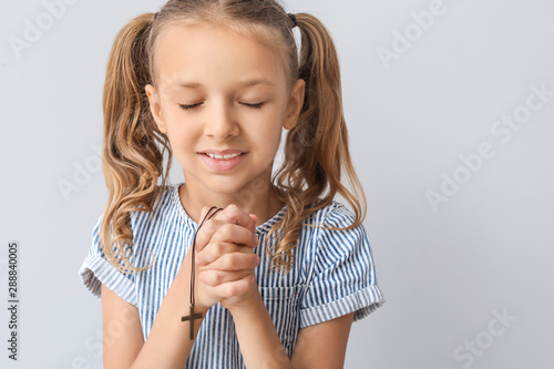 Praying little girl on ligh...