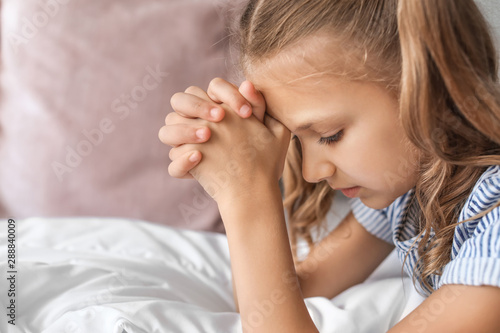Cute little girl praying in...