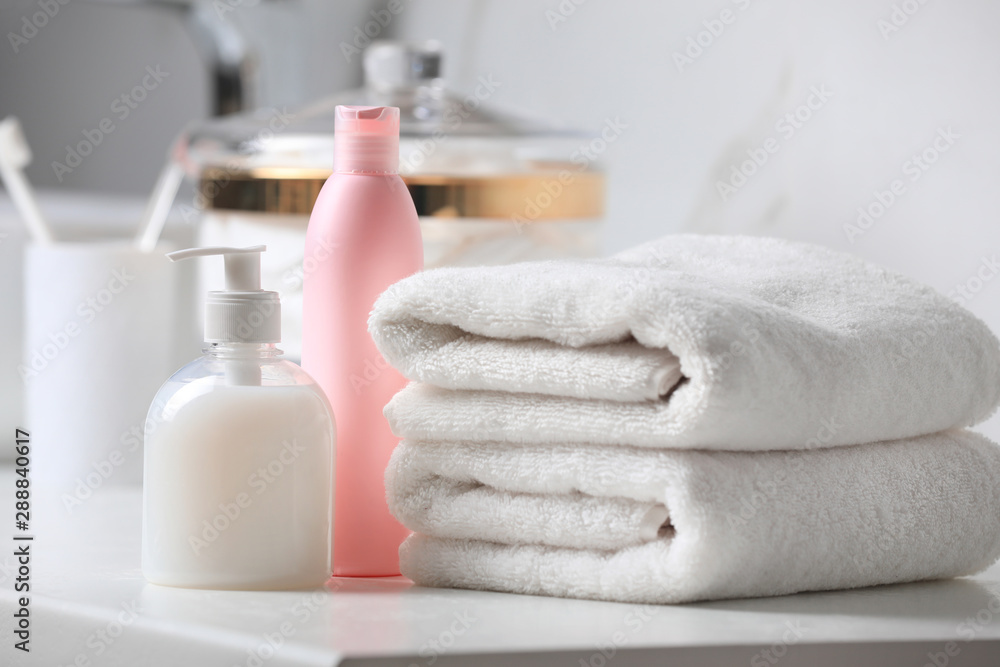 Folded towels and toiletries on white table in bathroom Folded towels and toiletries on white table in bathroom