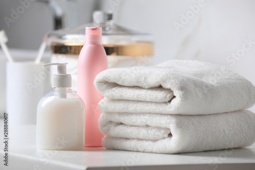 Folded towels and toiletries on white table in bathroom photo