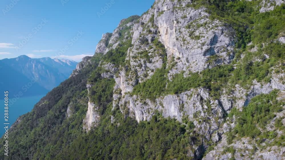 drone is flying back from cliff covered forest, placed near blue lake in sunny day, amazing landscape drone is flying back from cliff covered forest, placed near blue lake in sunny day, amazing landscape