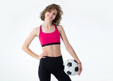Young sports woman with a soccer ball in her hands standing on a gray background. Play female football.