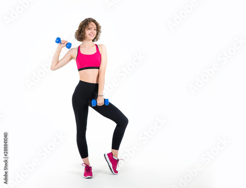 Young athletic woman doing exercises with dumbbell, standing on white.