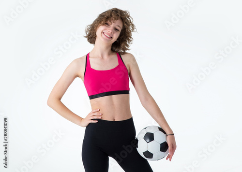 Young sports woman with a soccer ball in her hands standing on a gray background. Play female football.