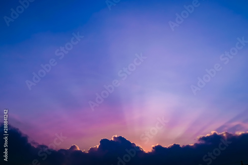 Beautiful colors of sunset sky with silhouette of cloud and sunlight rays and copy space .