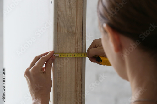 Fototapeta Woman holding a meter, measuring dimensions on plasterboard panel - DIY home imp