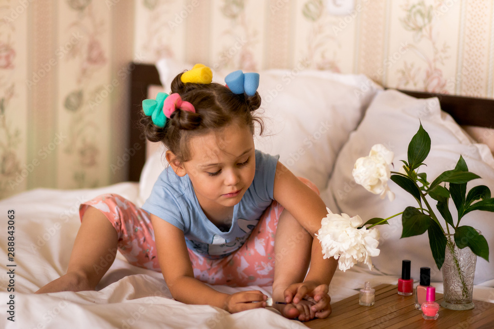 girl in pajamas and curlers paints nails girl in pajamas and curlers paints nails