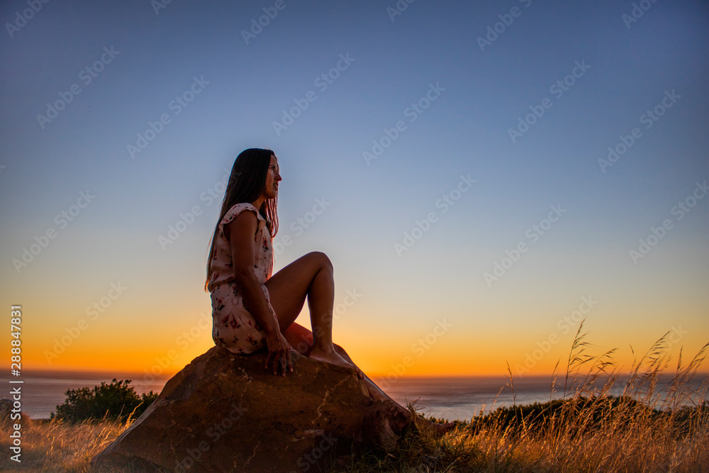 Silhouette of a beautiful woman playfully sitting on a rock at sunset or sunrise. Silhouette of a beautiful woman playfully sitting on a rock at sunset or sunrise.