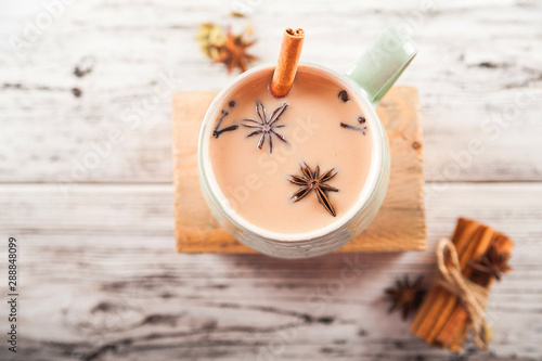 Details of still life in the home interior living room. Beautiful Cup of tea with milk, star anise, cinnamon on a wooden background. Cozy autumn-winter concept. Masala is a traditional hot spicy drink