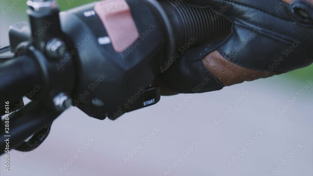 Close up. Biker in leather gloves start old-fashioned motorcycle. Man presses the start engine button on handlebar, oldscool bike or custom bike. Highway rider. Danger transport, transportation Close up. Biker in leather gloves start old-fashioned motorcycle. Man presses the start engine button on handlebar, oldscool bike or custom bike. Highway rider. Danger transport, transportation