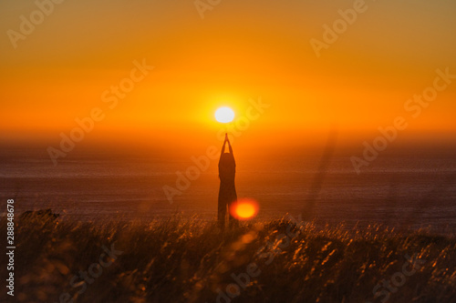 Silhouette of a beautiful woman standing and praying at sunset or sunrise.