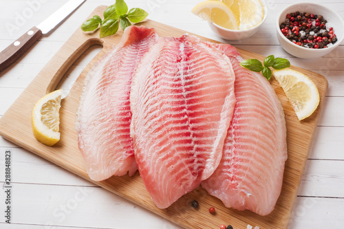 Photography Raw fish fillet of tilapia on a cutting Board with lemon and spices