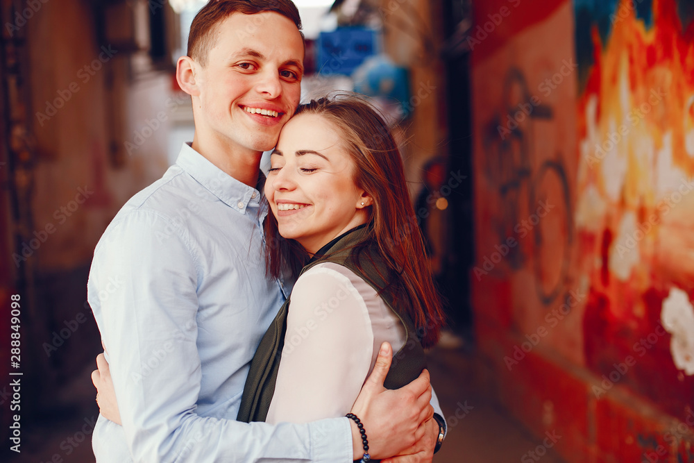 Fototapeta premium handsome young guy in a blue shirt standing in a urban summer city along with her cute girl in a white shirt