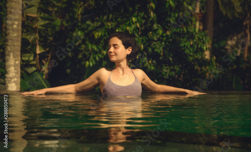 The girl in the infinity pool. Pool in the jungle. Holidays in Bali. The girl is tanning. Relax.