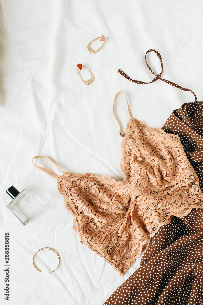 Flatlay fashionable female underwear, clothes and accessories on white  linen. Ginger bra, dress, perfume, earrings, bracelet, pillow. Top view  fashion lifestyle beauty collage. Stock Photo