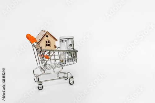 Property investment and house mortgage financial concept. buying, renting and selling apartments. real estate. Wooden house and dollar note in a supermarket trolley. Credit, affordable housing 