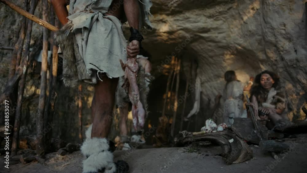 Tribe of Hunter-Gatherers Wearing Animal Skin Live in a Cave. Leader Brings Animal Prey from Hunting, Female Cooks Food on Bonfire, Girl Drawing on Wals Creating Art. Neanderthal Homo Sapiens Family Tribe of Hunter-Gatherers Wearing Animal Skin Live in a Cave. Leader Brings Animal Prey from Hunting, Female Cooks Food on Bonfire, Girl Drawing on Wals Creating Art. Neanderthal Homo Sapiens Family