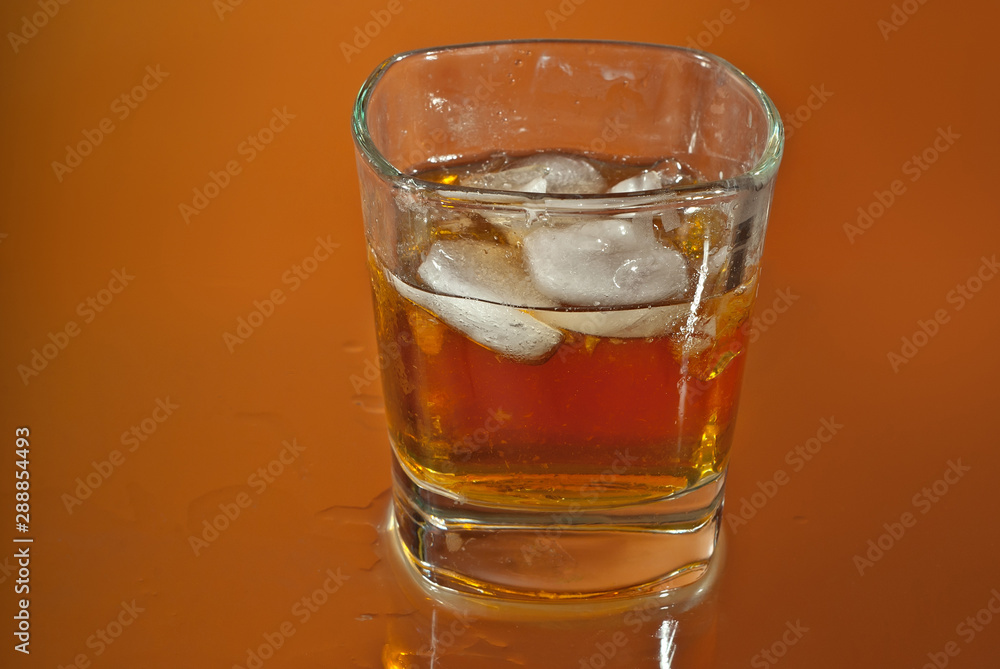 Alcoholic drink with ice in transparent glasses. Wine glass with cocktail isolated on orange background. Frozen drinks on glass table. Alcoholic drink with ice in transparent glasses. Wine glass with cocktail isolated on orange background. Frozen drinks on glass table.
