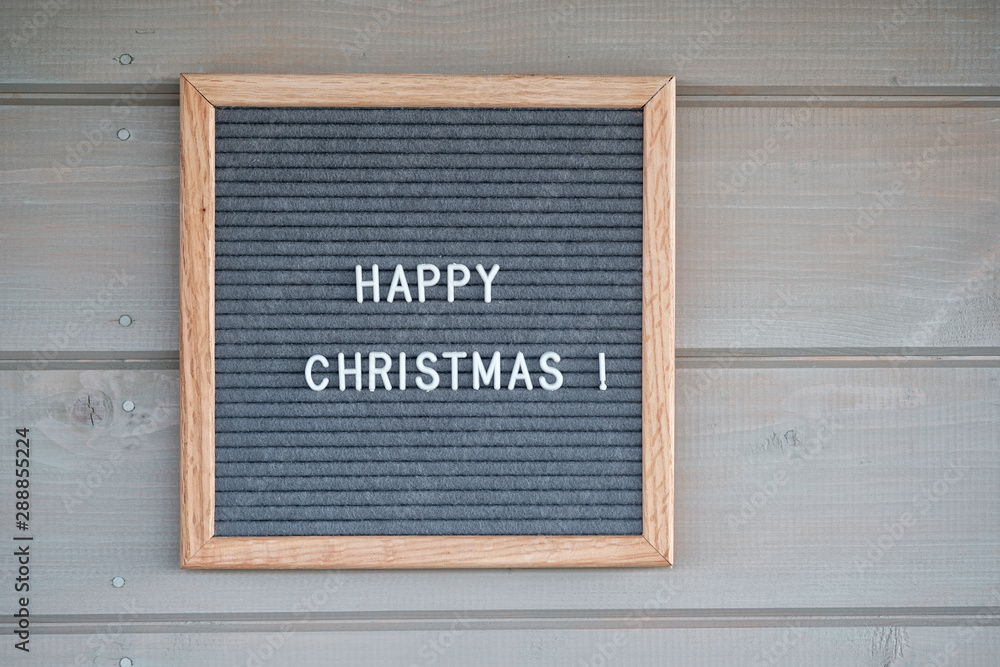 gray felt Board with English text Happy Christmas on the background of a wooden wall