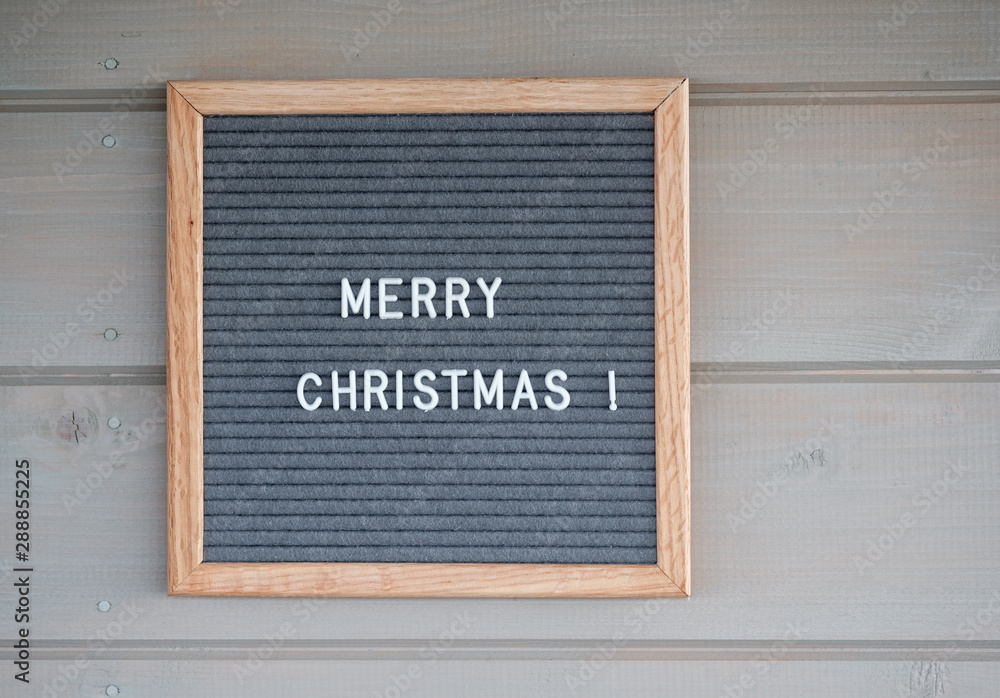 gray felt Board with English text Merry Christmas on the background of a wooden wall