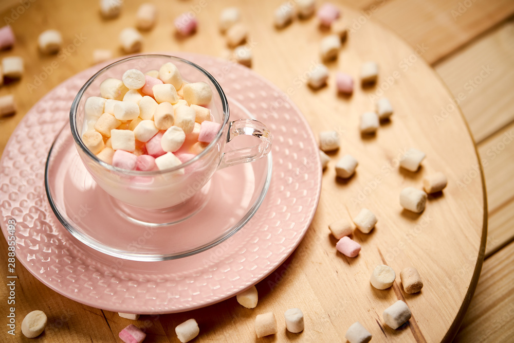 Cup with hot milk and colorful marshmallows on wooden table Cup with hot milk and colorful marshmallows on wooden table