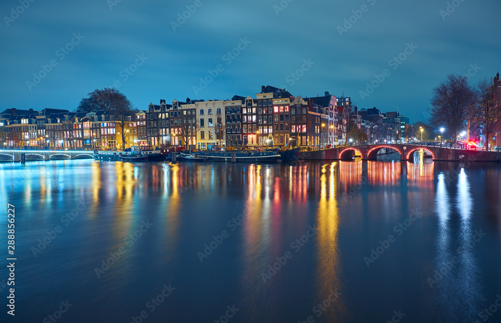 Traditional and historical buildings by the canal. Night cityscape in  Amsterdam.