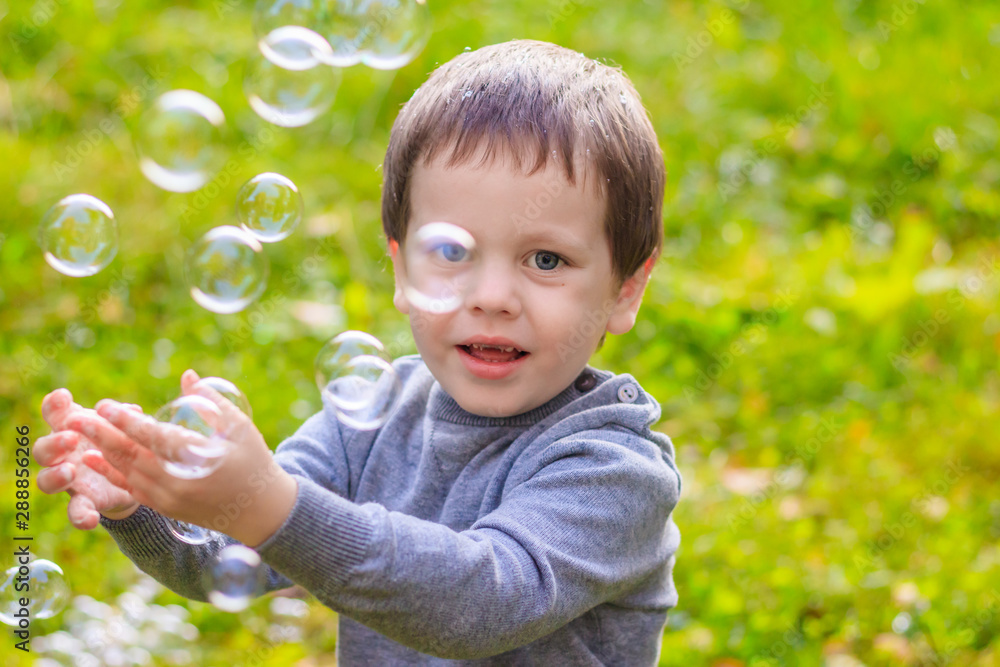 A boy on the street catches soap bubbles. Happy childhood. Children's games. A boy on the street catches soap bubbles. Happy childhood. Children's games.