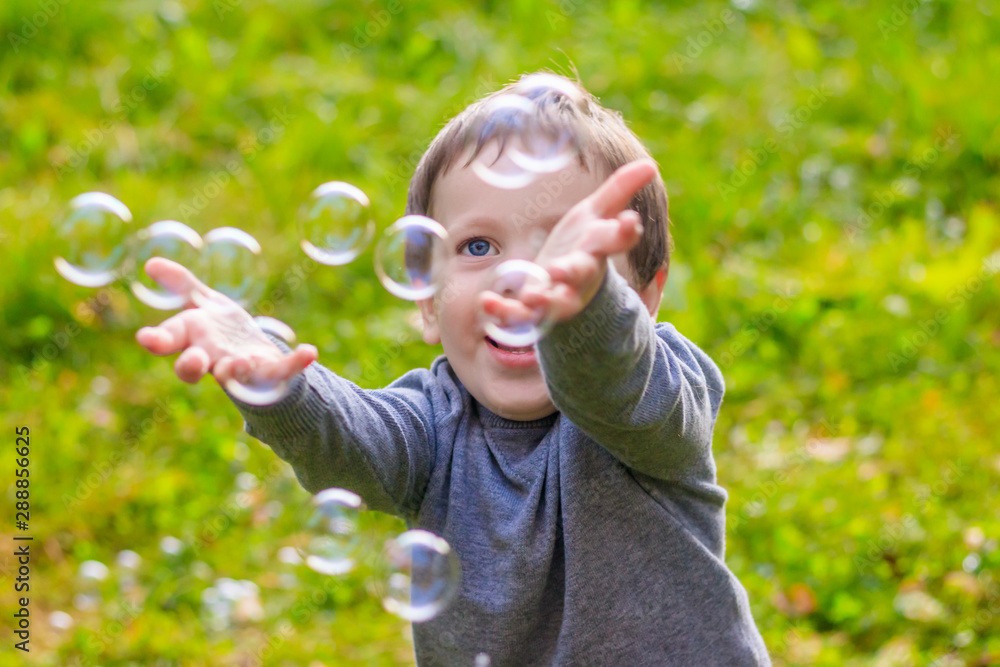 A boy on the street catches soap bubbles. Happy childhood. Children's games. A boy on the street catches soap bubbles. Happy childhood. Children's games.