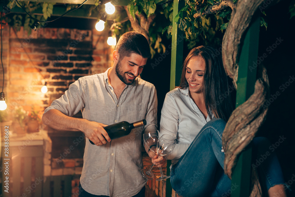 romantic couple drinking wine on backyard decking . evening scene