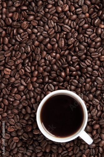 Coffee beans surrounding a coffee mug