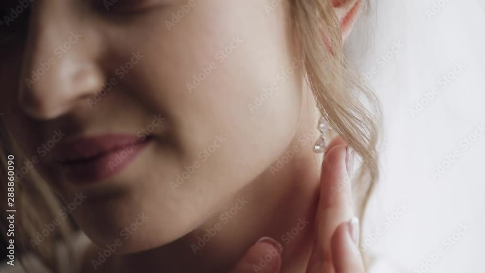 Beautiful and lovely bride in night gown and veil touches her earrings Beautiful and lovely bride in night gown and veil touches her earrings