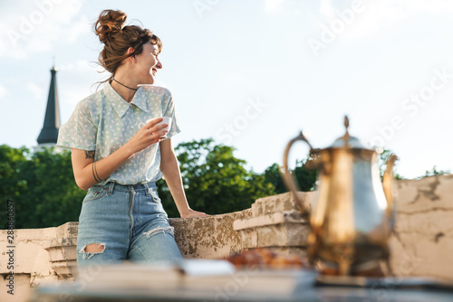 Young beautiful woman drinking coffee on a balcony.