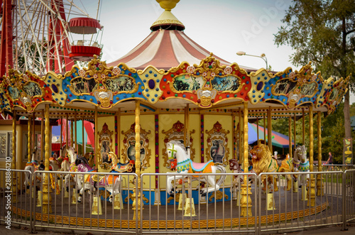 Children's carousel with horses. Bright summer photo of a children's attraction. Photo taken on a sunny summer day. City attraction for young children.