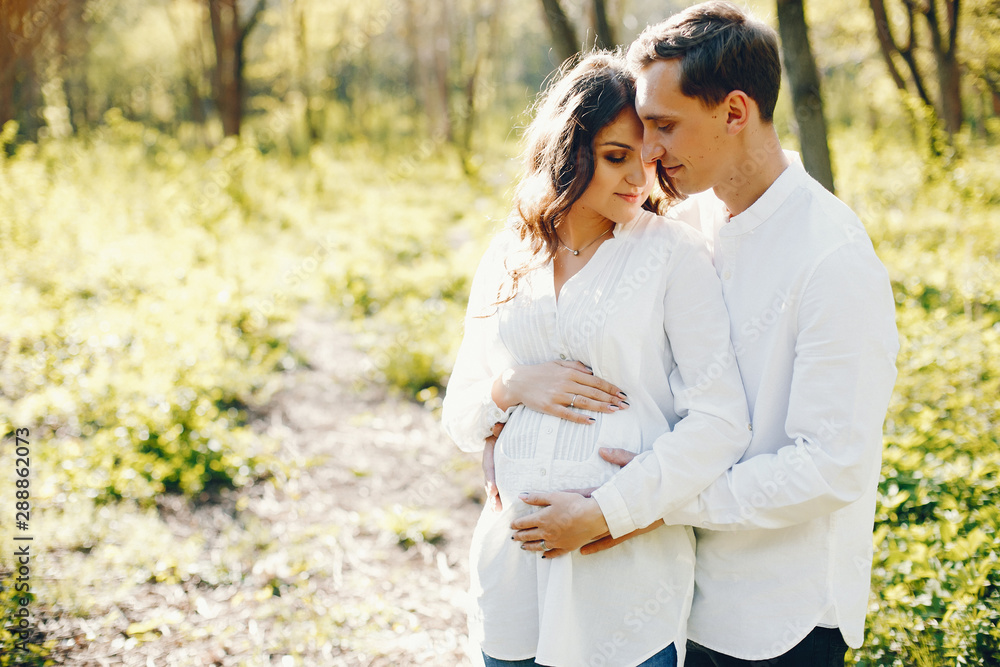 bright and happy pregnant woman walking in the park with her husband bright and happy pregnant woman walking in the park with her husband
