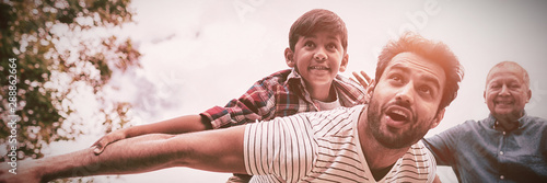 Foto Smiling grandfather looking at man giving piggy backing to son