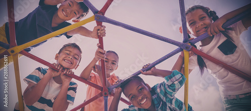 Portrait of happy schoolkids looking through dome climber