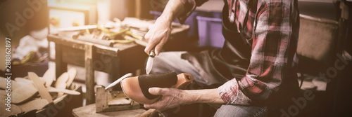 Schilderij op canvas Cobbler holding a knife and a shoe