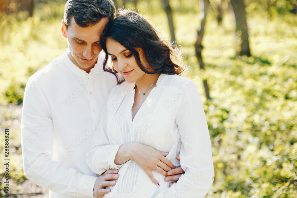 bright and happy pregnant woman walking in the park with her husband bright and happy pregnant woman walking in the park with her husband