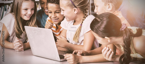 Billede på lærred School kids using laptop in library