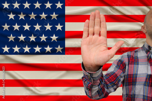 male hand with a gesture of protest, oaths against the backdrop of the US silk national flag, concept of denial and prohibition and prohibition, close-up, copy space