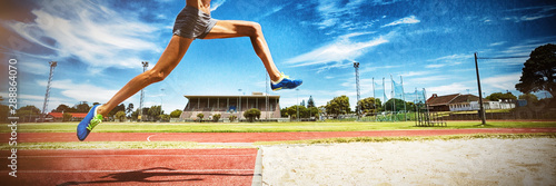 Female athlete performing a long jump photo