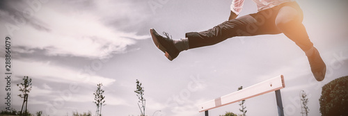 Tableau sur toile Businessman jumping a hurdle while running