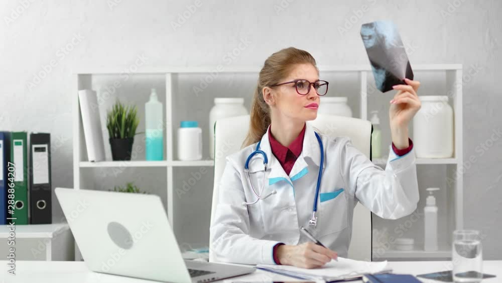 Busy female surgeon checking x-ray image taking note working at modern clinic room Busy female surgeon checking x-ray image taking note working at modern clinic room