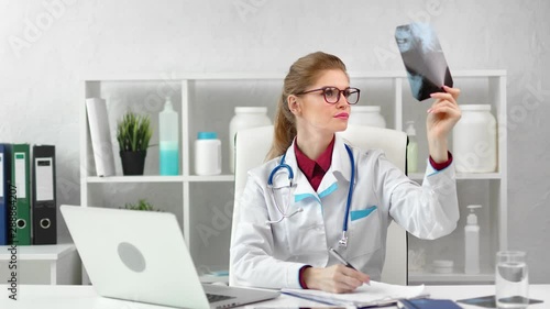 Wallpaper Mural Busy female surgeon checking x-ray image taking note working at modern clinic room Torontodigital.ca