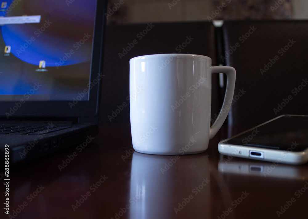 A cup of coffee on the table next to a laptop and mobile phone A cup of coffee on the table next to a laptop and mobile phone