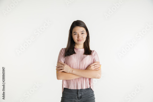 Beautiful female half-length portrait isolated on white studio background. Young emotional woman in casual clothes. Human emotions, facial expression concept. Standing with hands crossed, confident.