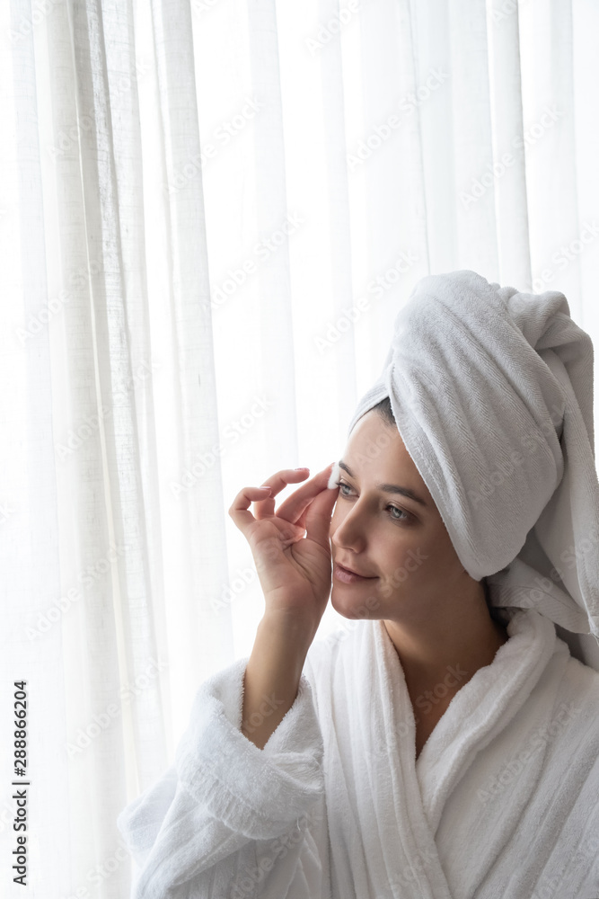 Beautiful young woman with towel cleaning skin with cotton pad or swab. Skin care routine concept Beautiful young woman with towel cleaning skin with cotton pad or swab. Skin care routine concept